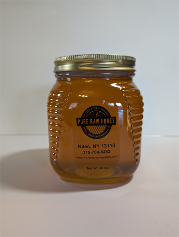 A jar of honey is sitting on the counter.